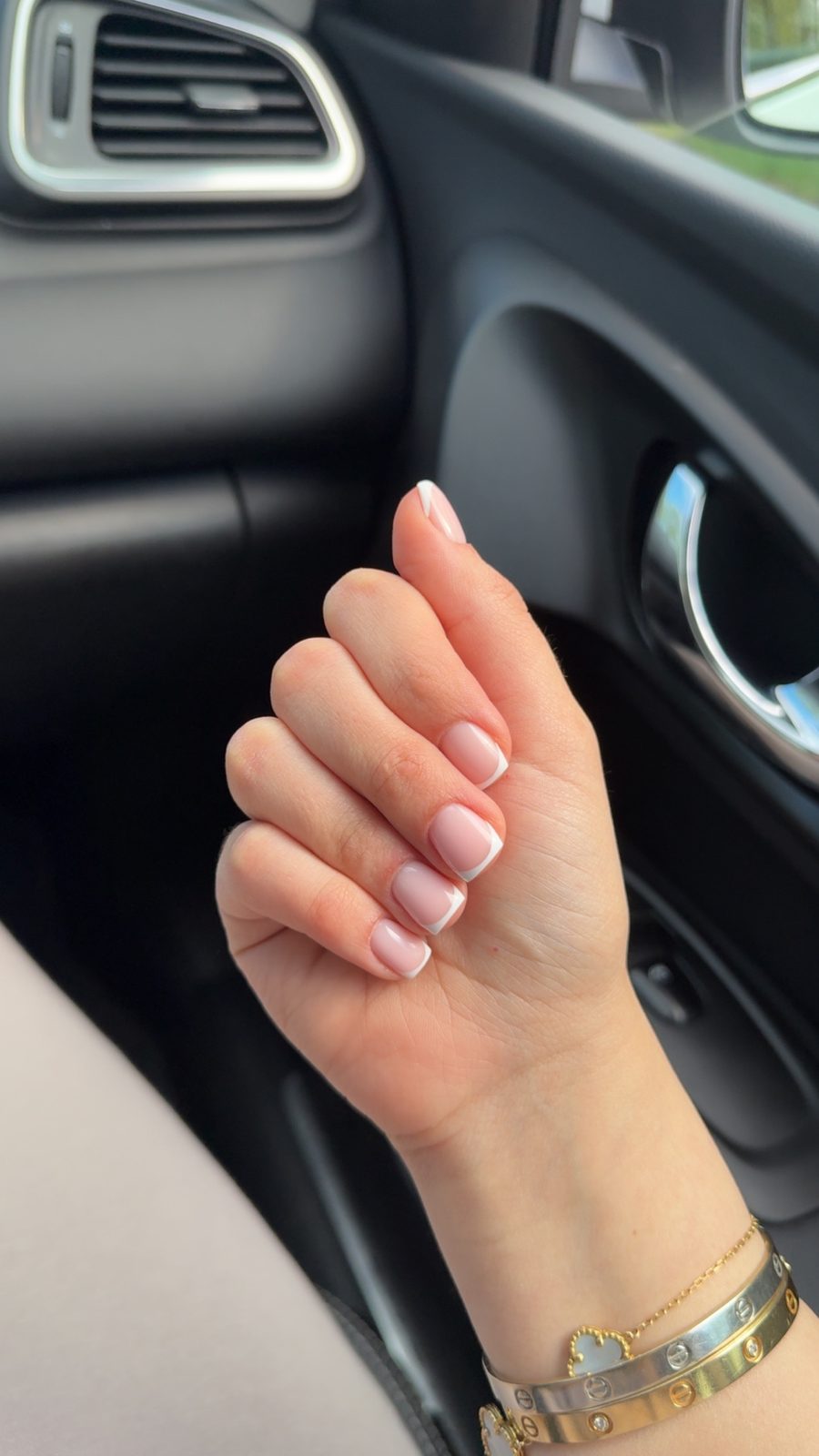 Hand met lichtroze nagels in de auto