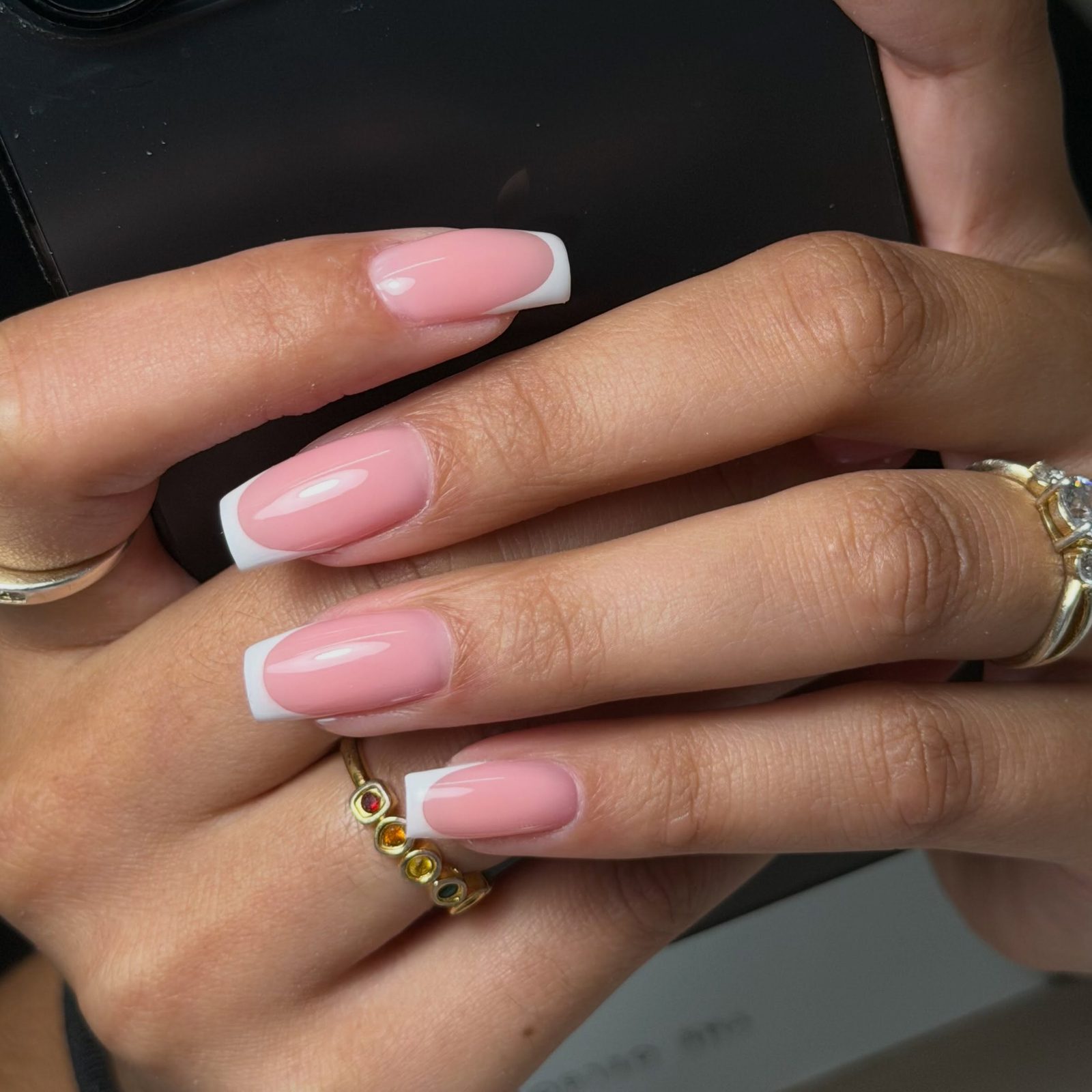 Roze nagels met een witte French tip, de hand houdt een telefoon vast