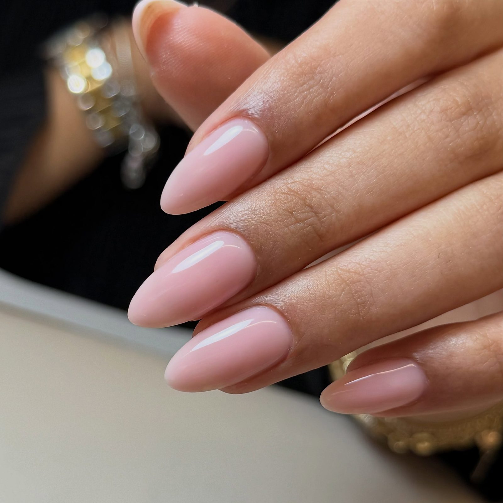 Glanzende amandelvormige nude nagels met een fijne witte rand, close-up